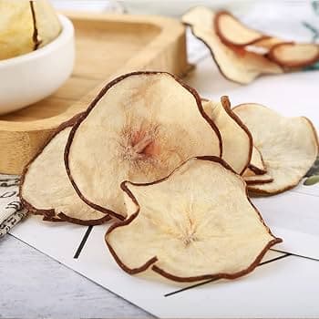 Thinly sliced dehydrated pear chips with dark brown edges arranged on a white surface.